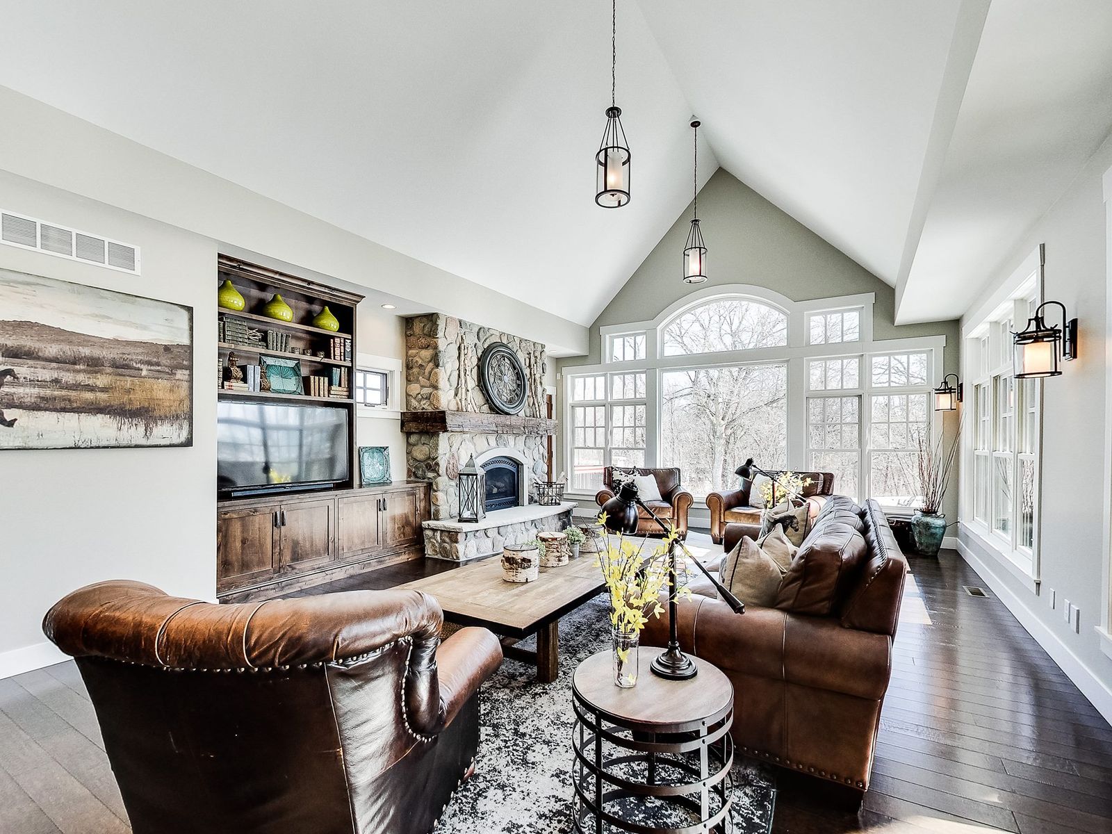 Vaulted great room with a stone fireplace, built-ins and walls of windows, an Ivy Lane Homes interior