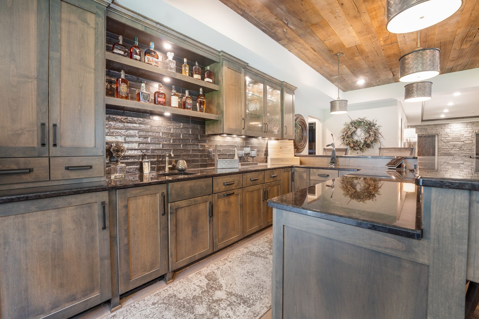 Lower-level family room with timber beams, reclaimed wood wall and stone fireplace, an Ivy Lane Homes interior